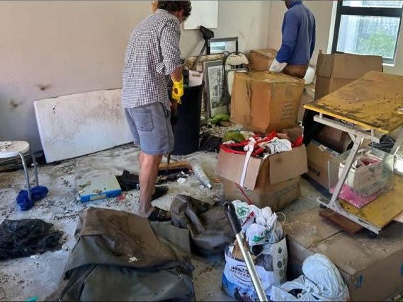 Two people clearing out a messy room